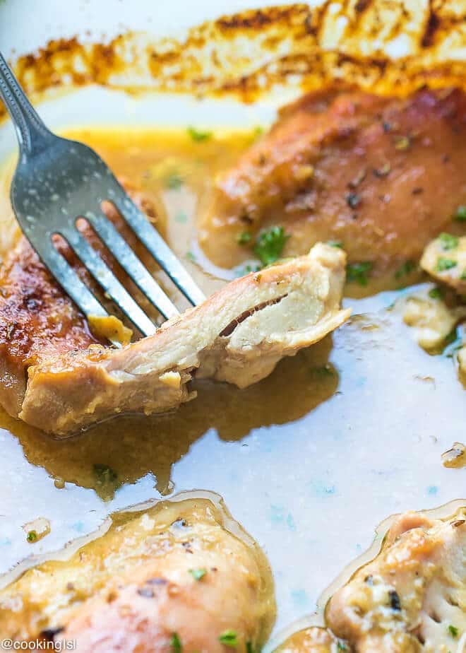 Juicy quick and easy to make with a few ingredients, Easy Oven Baked Honey Mustard Chicken Thighs Recipe. Cut chicken thigjs, to show how juicy it is.