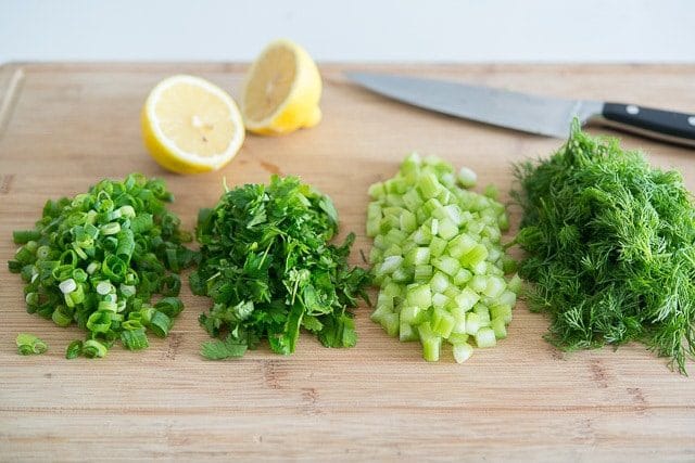 Chopped Scallions, Celery, Parsley, Herbs, and Lemon on Wooden Board