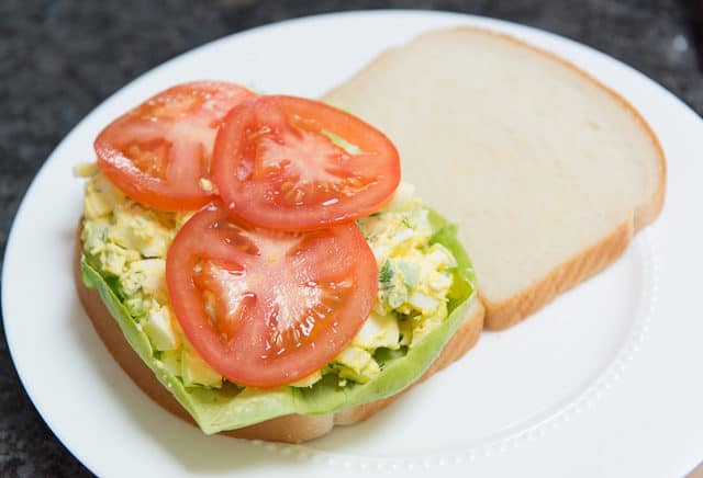 Slices of White Bread with Lettuce, Egg Salad, and Sliced Tomatoes